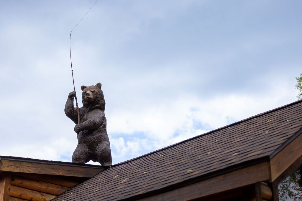 A sculpture of a standing black bear holding a fishing rod on the roof of a building at Snake River Cabins.