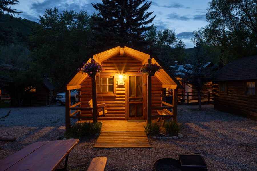 A log cabin illuminated under front porch lights at Snake River Cabins