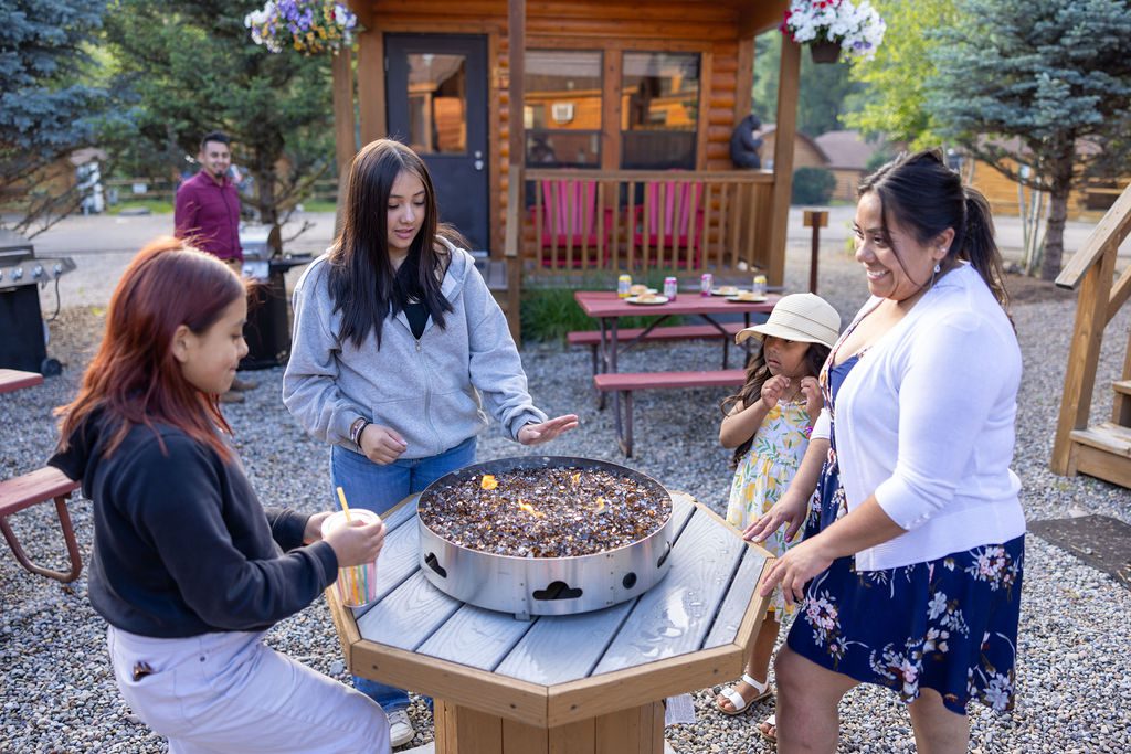A mother and three girls warm their hards around a propane fire pit at Snake River Cabins.